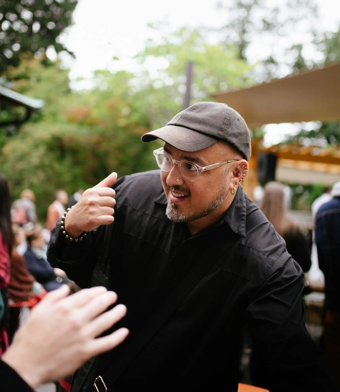 Man in black shirt and cap gestures enthusiastically.